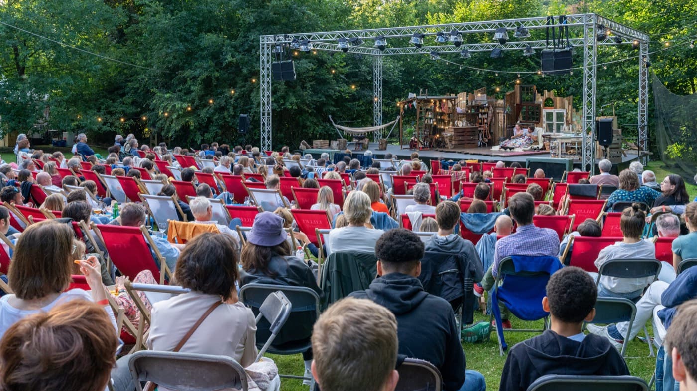 Le public dans les chaises longues rouges, face à la scène dans les arbres Photo Il est temps d'en rire saison été