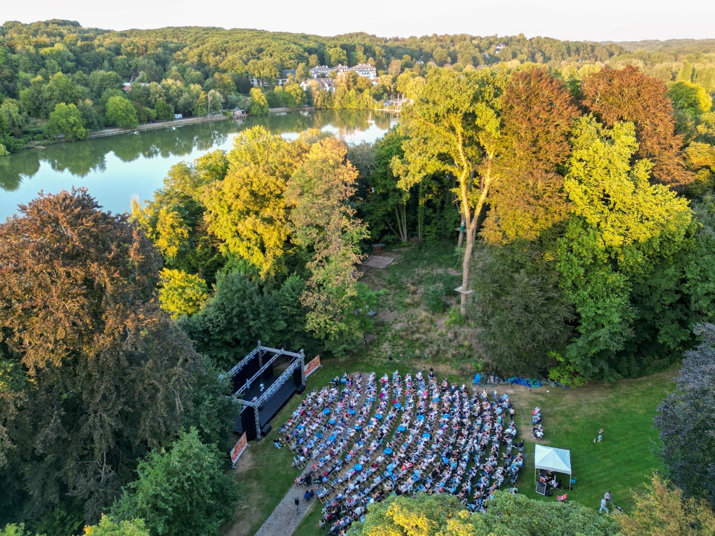Vue du ciel : la scène et le public dans le parc, au bord du lac de Genval Photo Il est temps d'en rire saison été