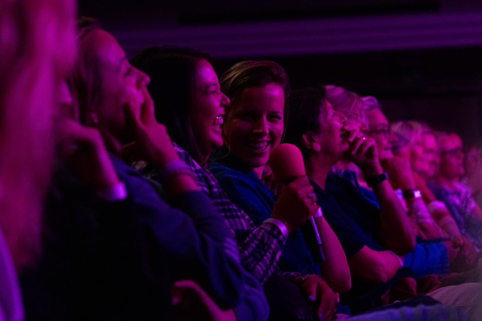 Des spectatrices rient dans la salle, sous une lumière violette Il est temps d'en rire. Photo de la saison d'hiver